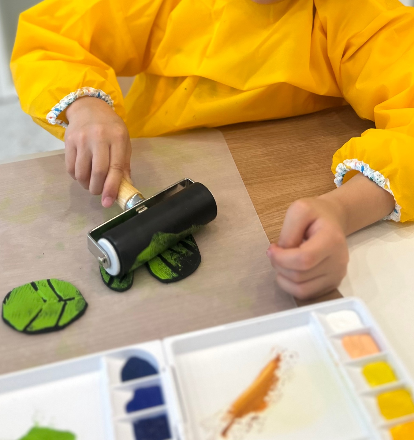 롤러로 나뭇잎 모양을 찍는 판화 수업 장면